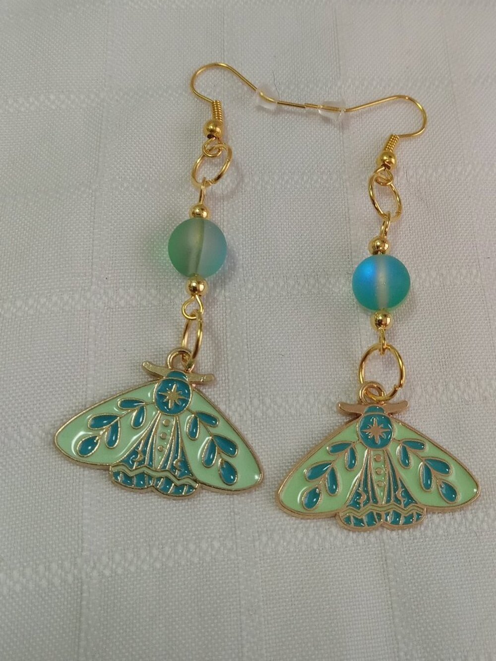 Handmade gold-colored earrings with multicolored enameled butterflies and beads